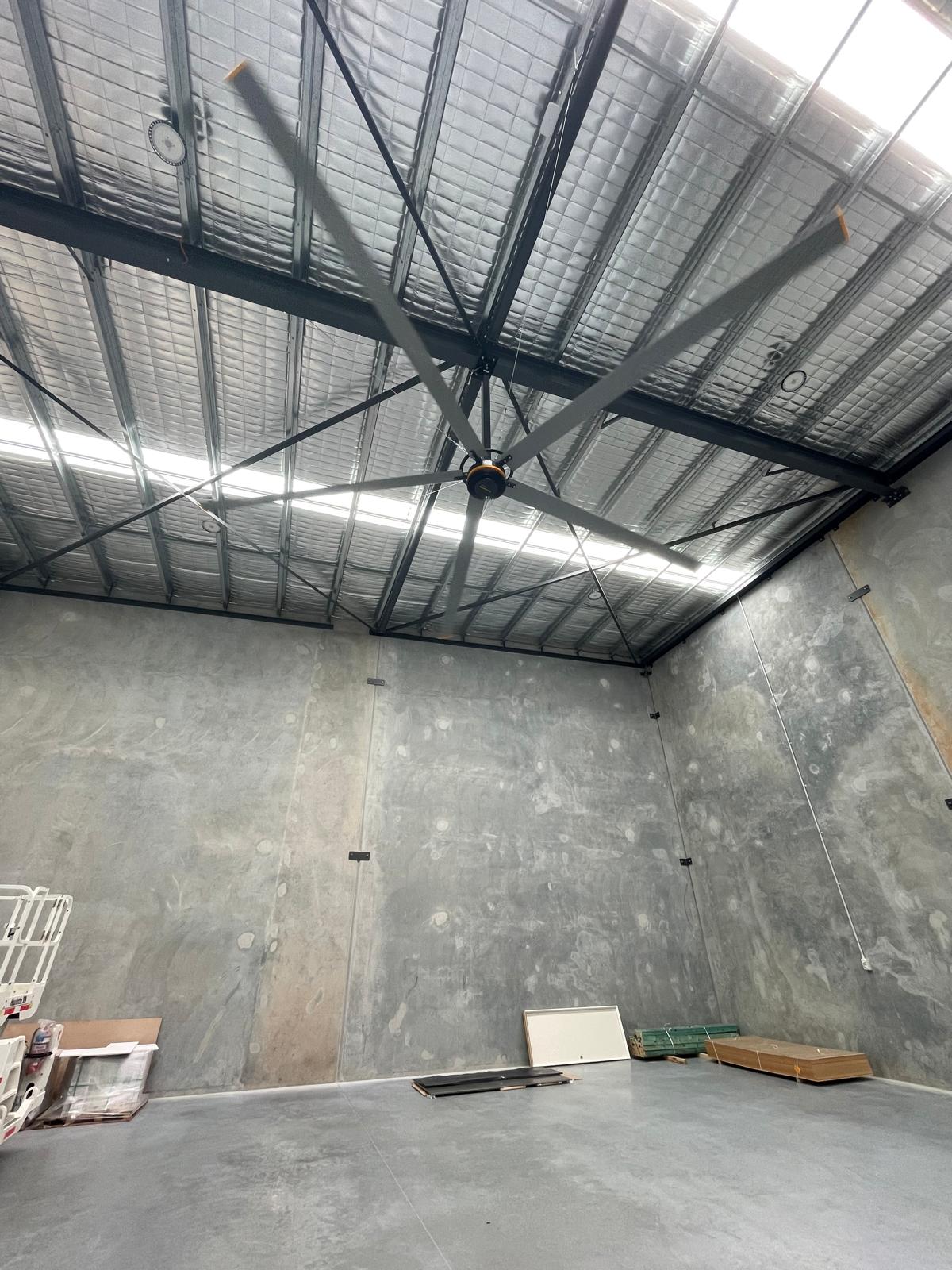 Large industrial ceiling fan mounted on metal ceiling beams in concrete warehouse Spring Hill